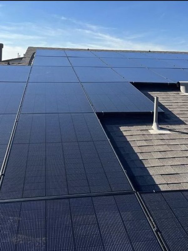 Rooftop solar panels under clear blue sky.