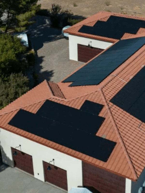 House with solar panels and surrounding landscape.